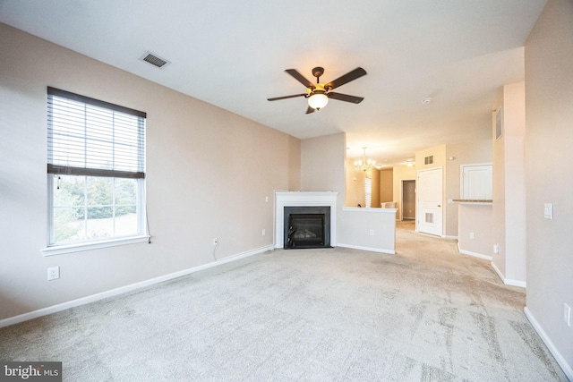 unfurnished living room with ceiling fan with notable chandelier and light colored carpet