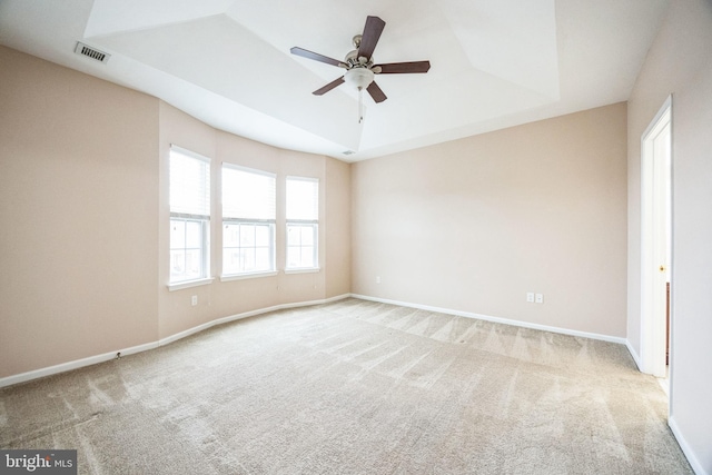 carpeted spare room with ceiling fan and a raised ceiling