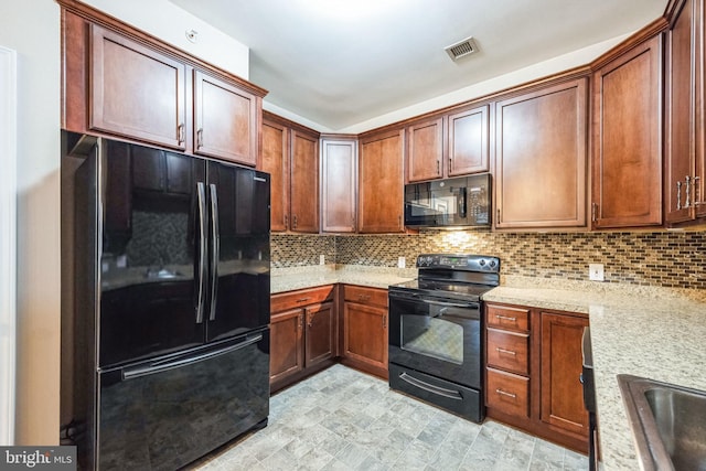 kitchen with light stone countertops, decorative backsplash, black appliances, and sink