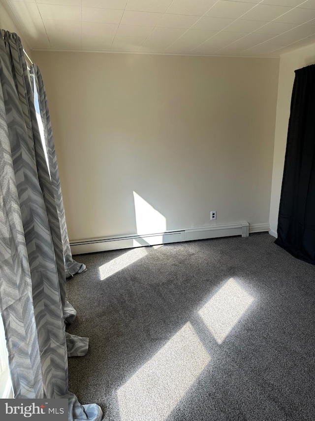 carpeted spare room featuring a baseboard heating unit