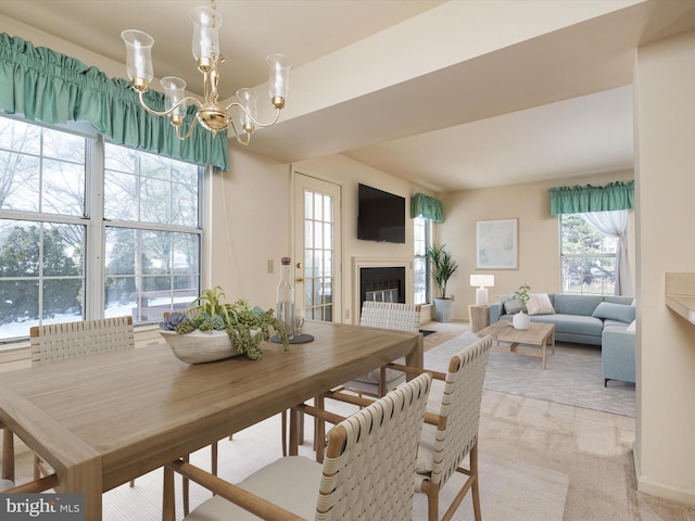 carpeted dining room featuring a healthy amount of sunlight and an inviting chandelier