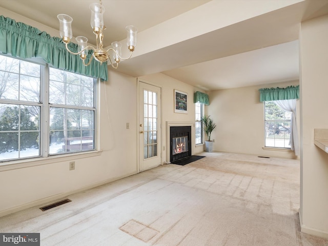 unfurnished living room featuring an inviting chandelier and carpet floors