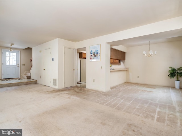 unfurnished living room featuring light colored carpet and a chandelier