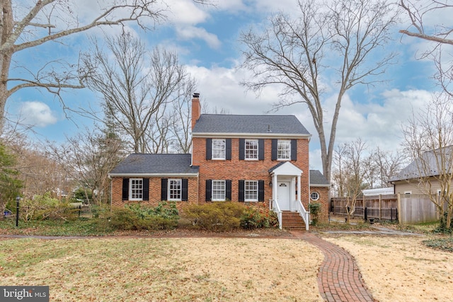 4901 Stillwell Ave, Alexandria, VA 22309 - colonial-style house with a chimney, fence, a shingled roof, a front lawn, and brick siding
