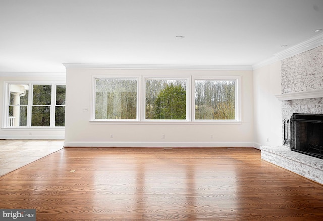 unfurnished living room featuring baseboards, a fireplace, ornamental molding, and wood finished floors