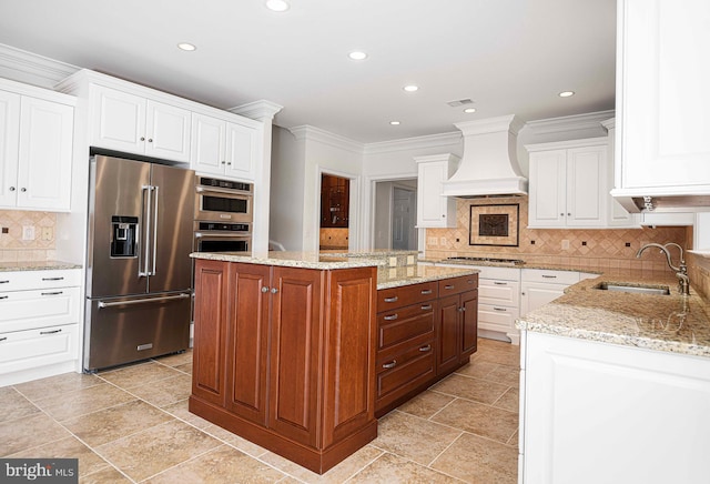 kitchen featuring appliances with stainless steel finishes, a center island, custom exhaust hood, white cabinetry, and a sink