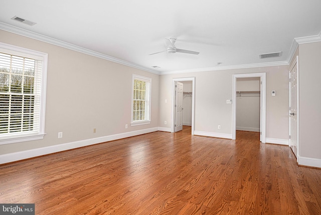 unfurnished bedroom with crown molding, multiple windows, visible vents, and wood finished floors