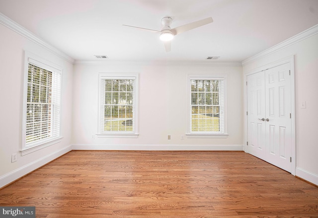 unfurnished room with light wood-style floors, crown molding, and plenty of natural light