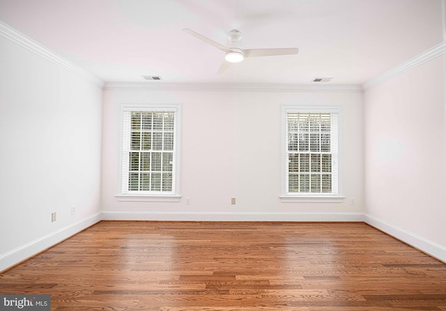 unfurnished room with visible vents, crown molding, baseboards, and wood finished floors