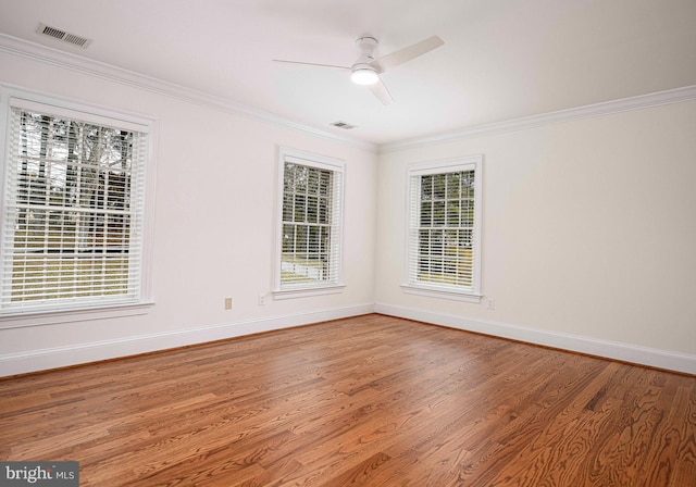 spare room featuring a wealth of natural light, visible vents, crown molding, and wood finished floors