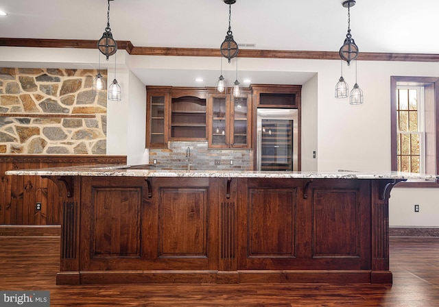 bar featuring baseboards, dark wood-style floors, tasteful backsplash, refrigerator with glass door, and pendant lighting