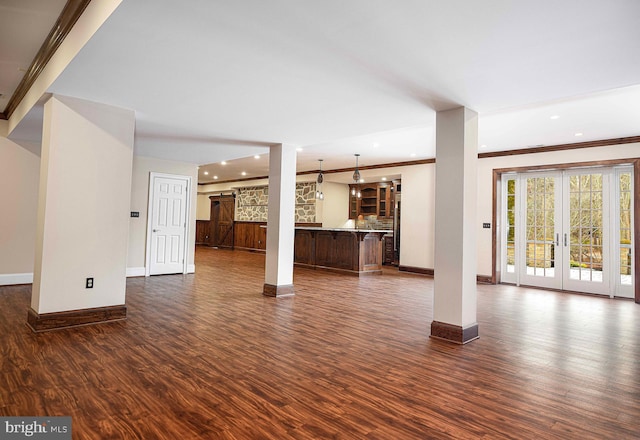 unfurnished living room featuring baseboards, ornamental molding, dark wood-style flooring, and french doors