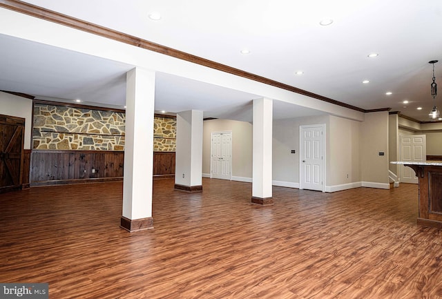 finished basement with baseboards, dark wood finished floors, and crown molding