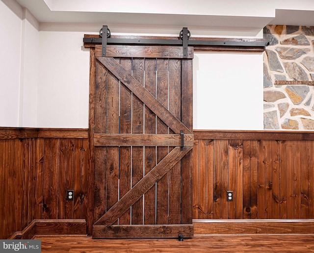 details featuring wood finished floors, a wainscoted wall, wood walls, and a barn door