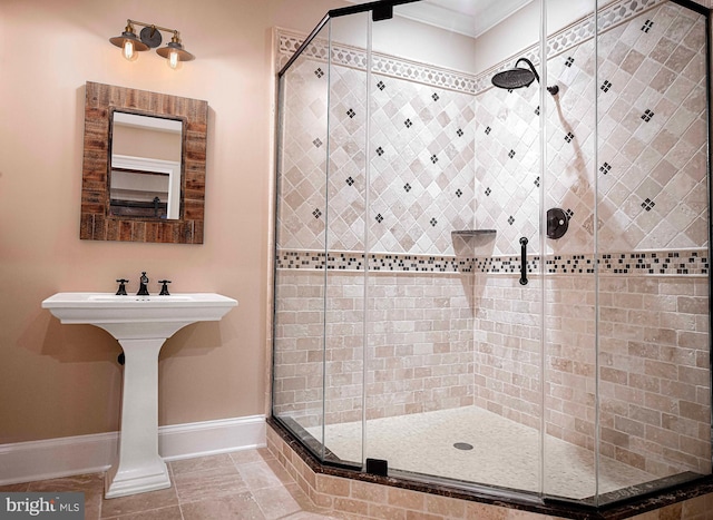 bathroom with ornamental molding, a shower stall, and baseboards