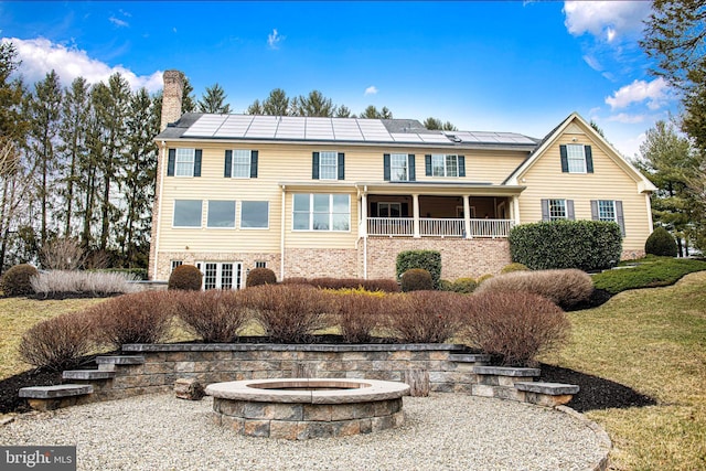 back of house featuring a chimney and a fire pit