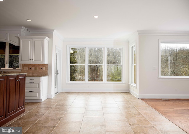 kitchen featuring white cabinetry, decorative backsplash, crown molding, and dark stone counters