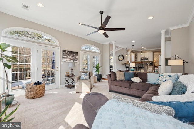 carpeted living room with crown molding, french doors, ceiling fan, and ornate columns