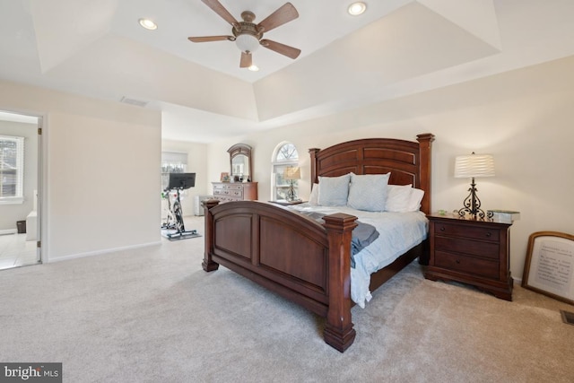 carpeted bedroom featuring ceiling fan and a raised ceiling