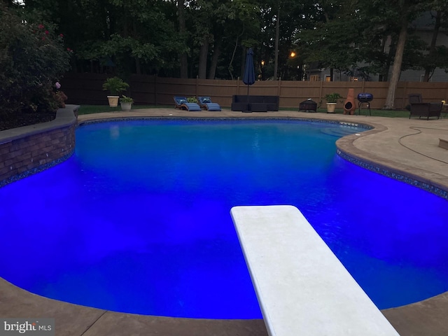 view of pool with a diving board and a patio