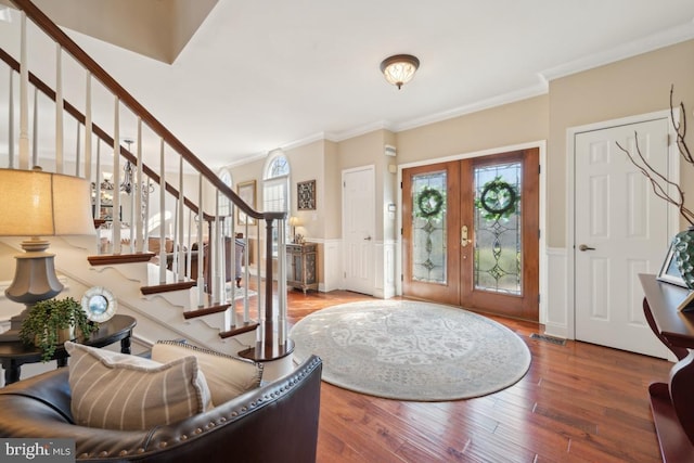 foyer featuring hardwood / wood-style floors, crown molding, french doors, and a healthy amount of sunlight