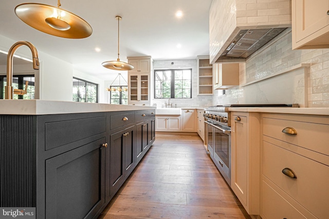 kitchen with double oven range, custom exhaust hood, light hardwood / wood-style floors, backsplash, and pendant lighting