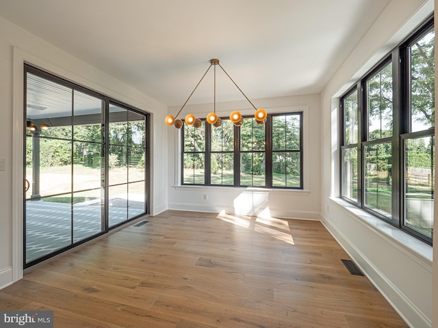 unfurnished dining area with wood-type flooring and a chandelier