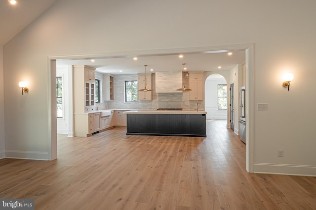 kitchen with tasteful backsplash, light wood-type flooring, lofted ceiling, hanging light fixtures, and a kitchen island