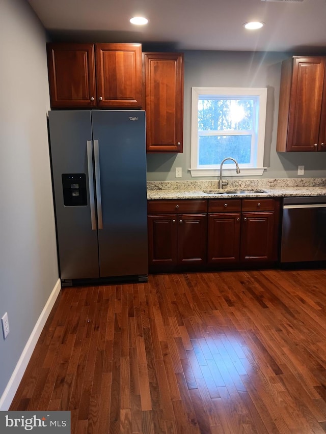 kitchen featuring light stone countertops, sink, stainless steel appliances, and dark hardwood / wood-style floors