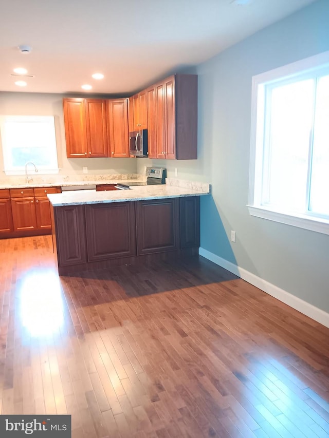 kitchen featuring appliances with stainless steel finishes, dark hardwood / wood-style flooring, and kitchen peninsula