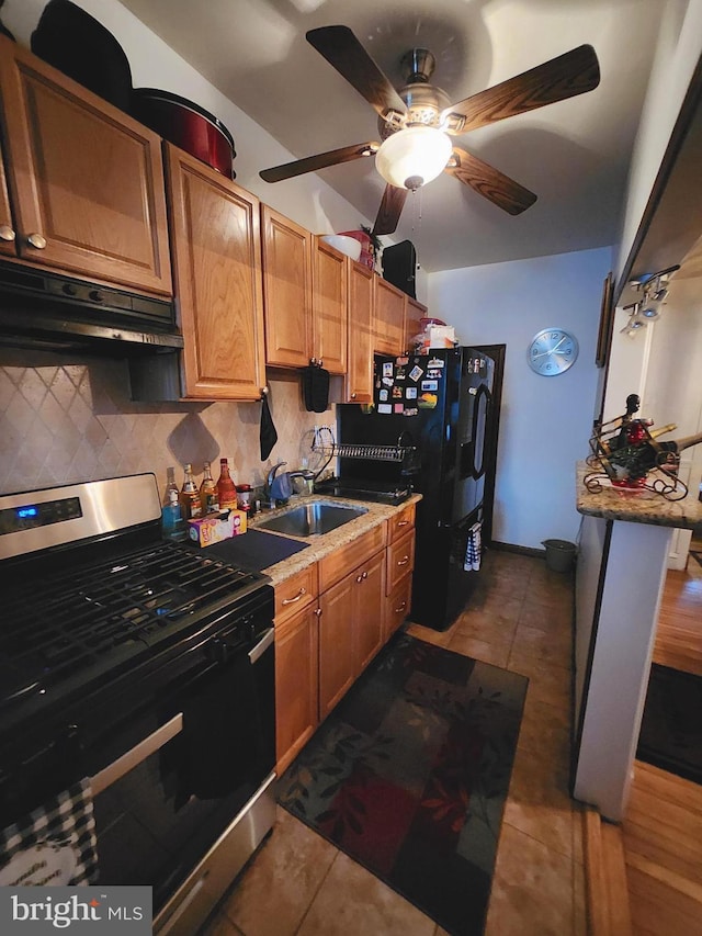 kitchen with backsplash, sink, gas stove, and dark tile patterned floors