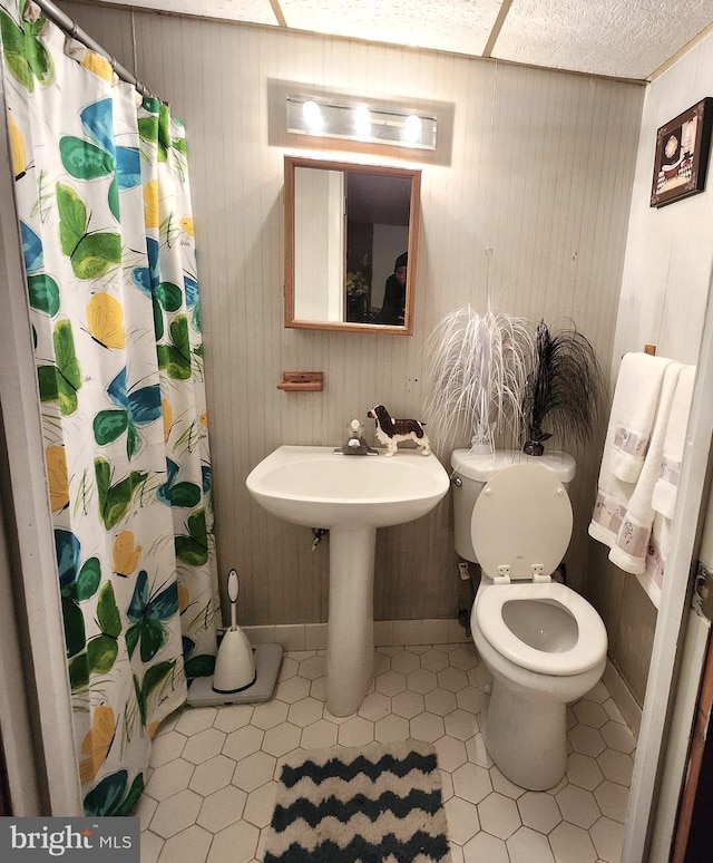 bathroom featuring a shower with curtain, tile patterned floors, and toilet