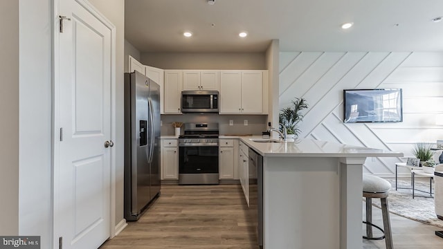 kitchen with a breakfast bar, kitchen peninsula, stainless steel appliances, and white cabinetry