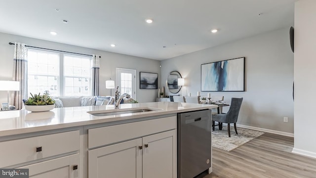 kitchen featuring stainless steel dishwasher, light hardwood / wood-style floors, white cabinetry, and sink