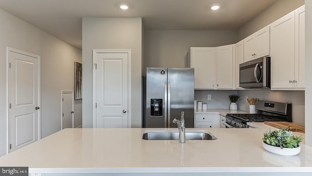 kitchen with kitchen peninsula, sink, white cabinetry, and stainless steel appliances