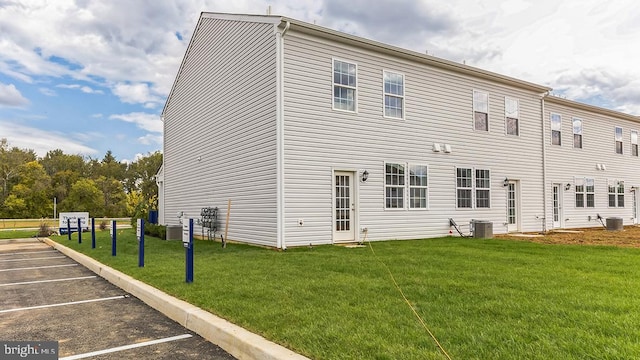 back of property featuring central AC and a yard