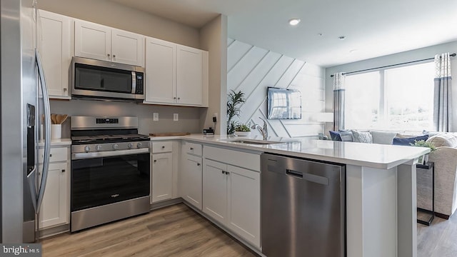 kitchen with kitchen peninsula, stainless steel appliances, white cabinets, and sink