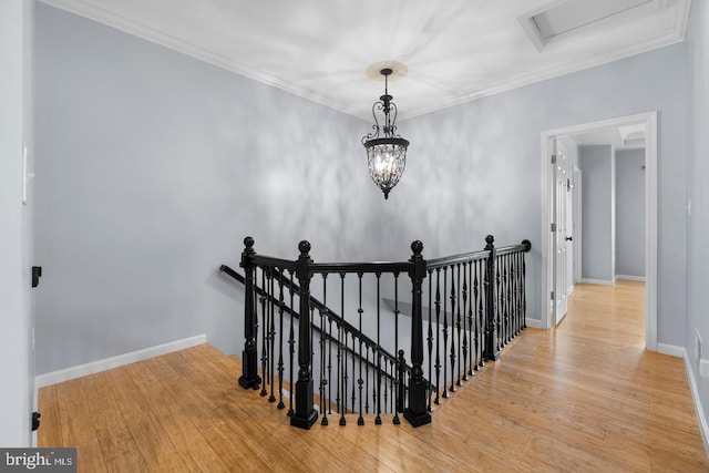 stairs with an inviting chandelier, ornamental molding, and hardwood / wood-style flooring