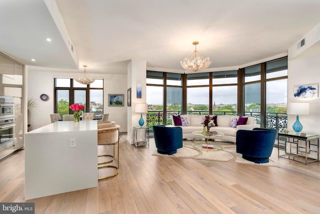 living room featuring a wall of windows, light hardwood / wood-style flooring, and an inviting chandelier