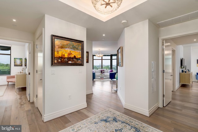 hallway featuring hardwood / wood-style flooring and a chandelier