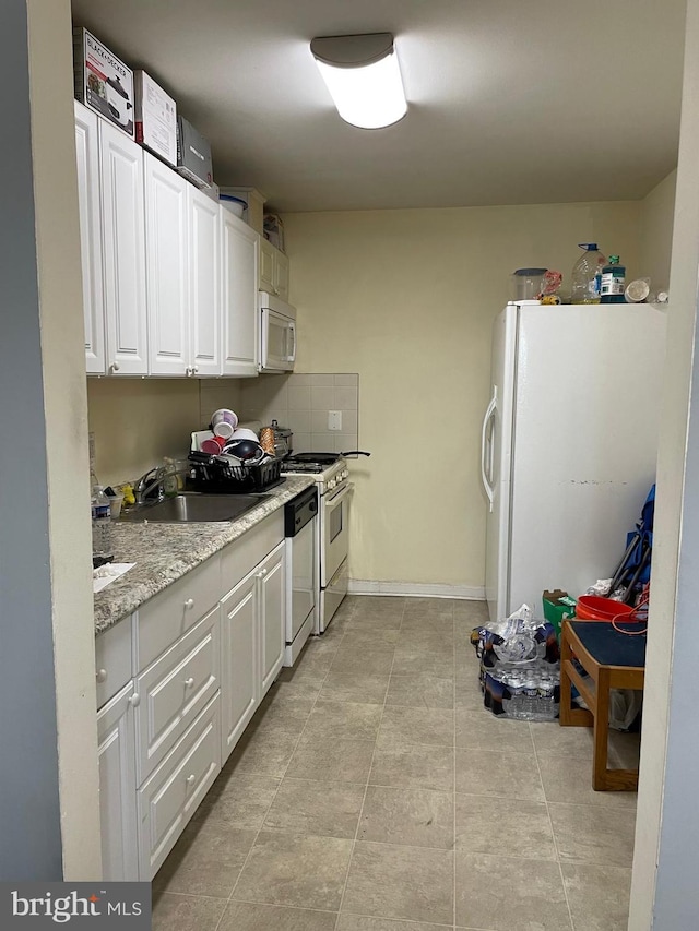 kitchen with white cabinets, light stone countertops, white appliances, and sink