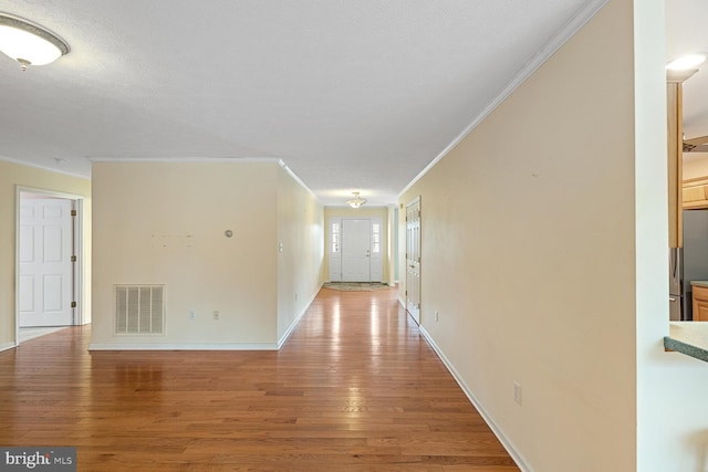 corridor featuring ornamental molding, a textured ceiling, and light hardwood / wood-style flooring