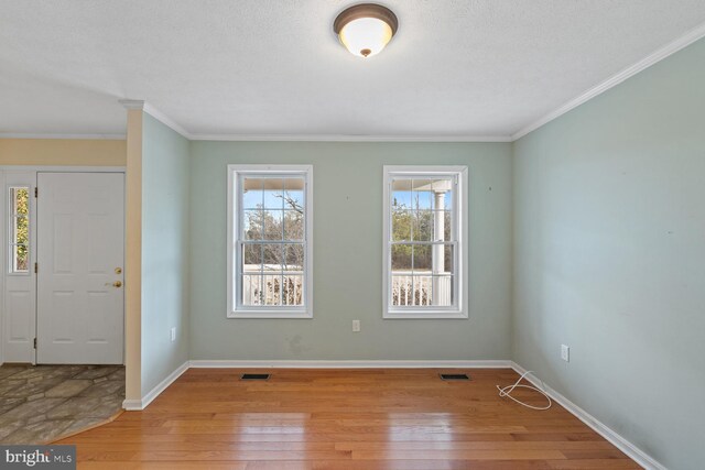 foyer entrance with crown molding, a textured ceiling, and light wood-type flooring