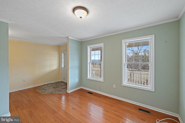 spare room featuring crown molding, a textured ceiling, and light hardwood / wood-style floors