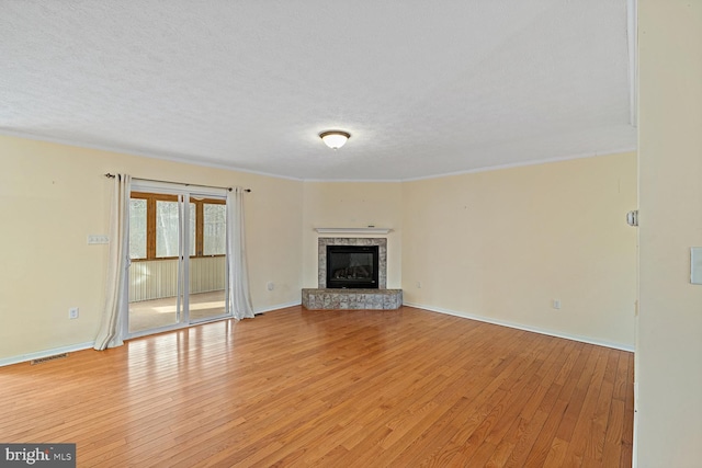 unfurnished living room featuring ornamental molding, light hardwood / wood-style floors, and a textured ceiling