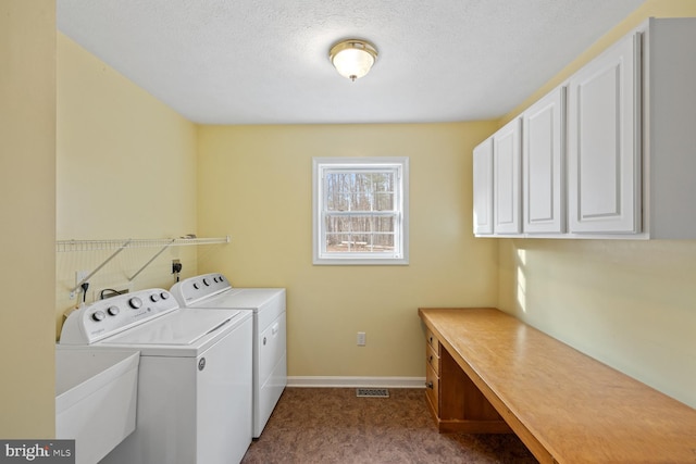 clothes washing area featuring washing machine and clothes dryer, sink, cabinets, light carpet, and a textured ceiling