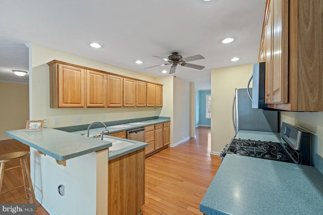 kitchen featuring a breakfast bar, ceiling fan, stainless steel appliances, light hardwood / wood-style floors, and kitchen peninsula