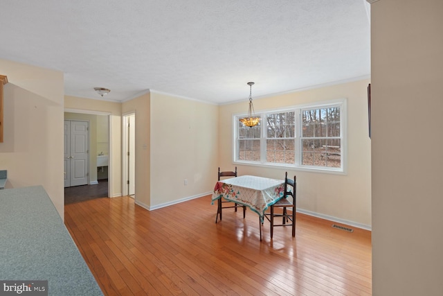 dining area featuring hardwood / wood-style floors, crown molding, a notable chandelier, and a textured ceiling