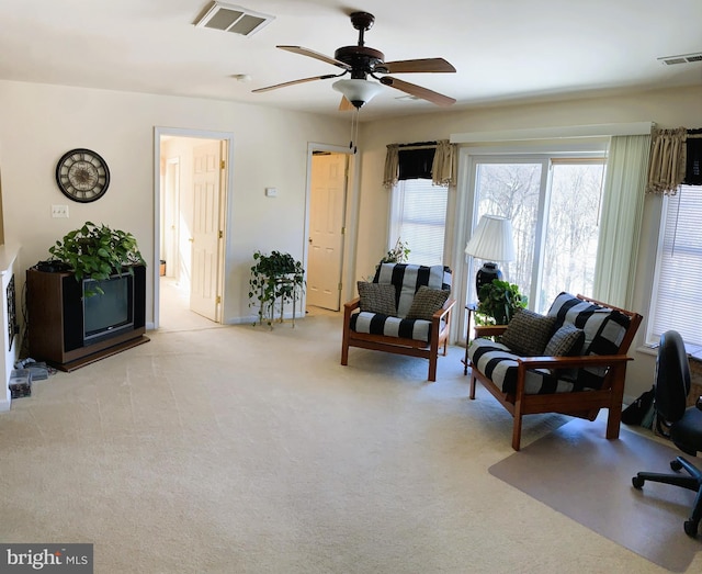 living area featuring light colored carpet and ceiling fan