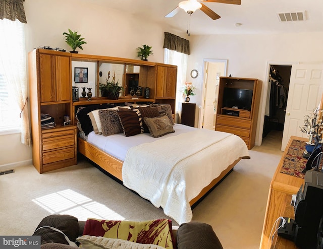 carpeted bedroom featuring ceiling fan, a spacious closet, and a closet